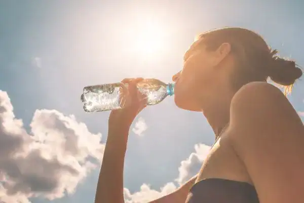 Hydration: The Secret Ingredient for a Toned Stomach and Enhanced Fitness 3 Image of woman drinking water to hydrate Tetbury after run.